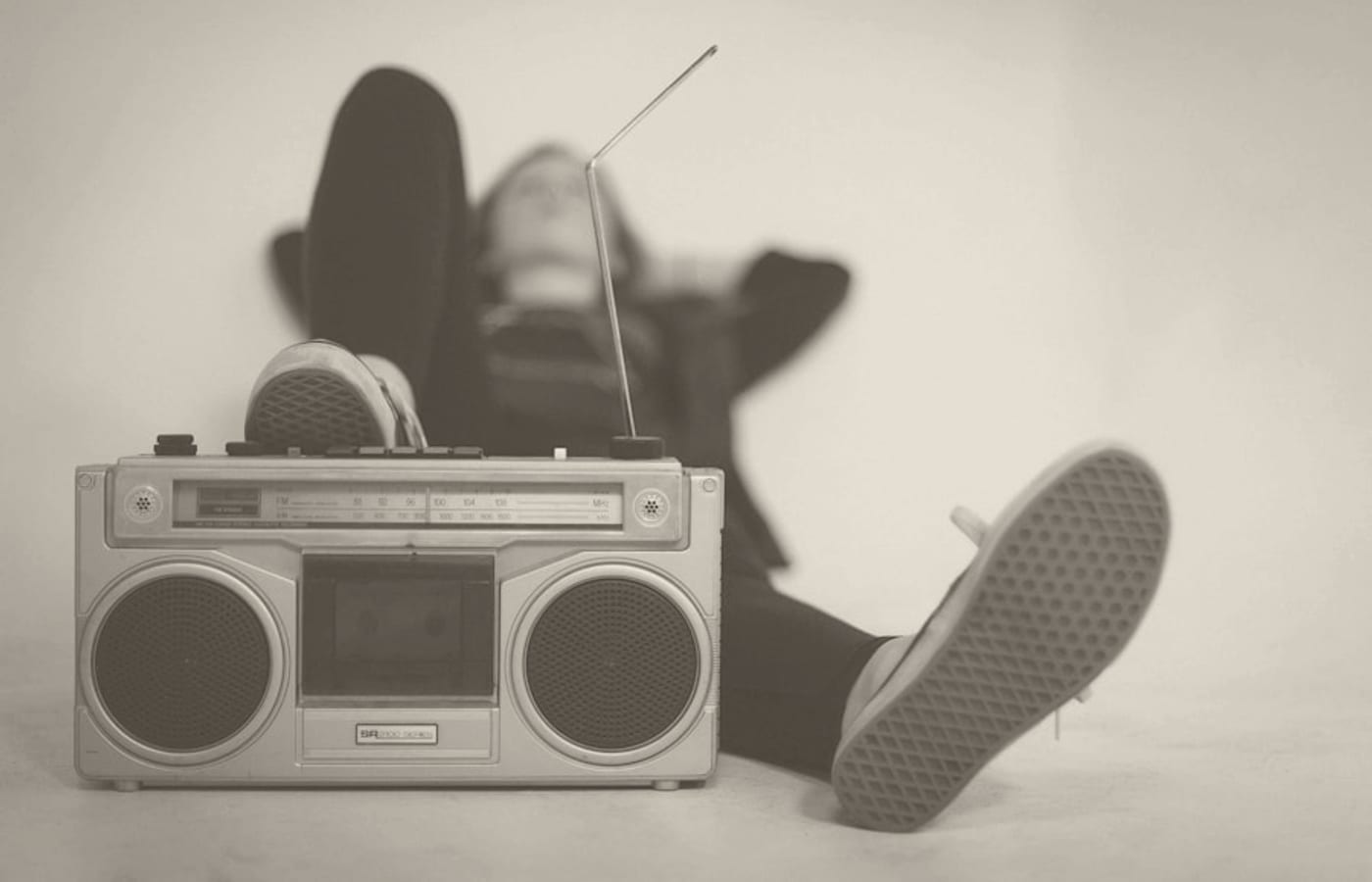 Pessoa deitada ao lado de um rádio portátil antigo